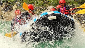 Un grupo de personas en balsas navegando por un río con agua salpicando.