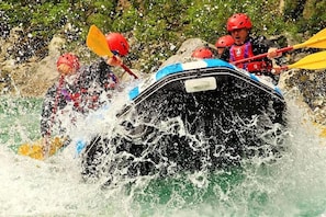 A group of people in a raft navigating through a river with splashing water.