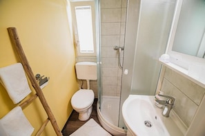 A bathroom with a toilet, shower, and sink.