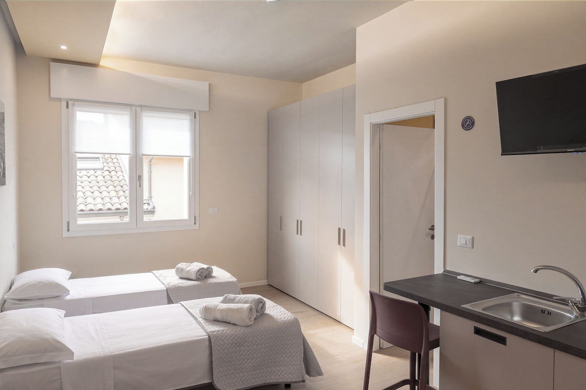 Habitación de hotel con dos camas, kitchenette y televisión.