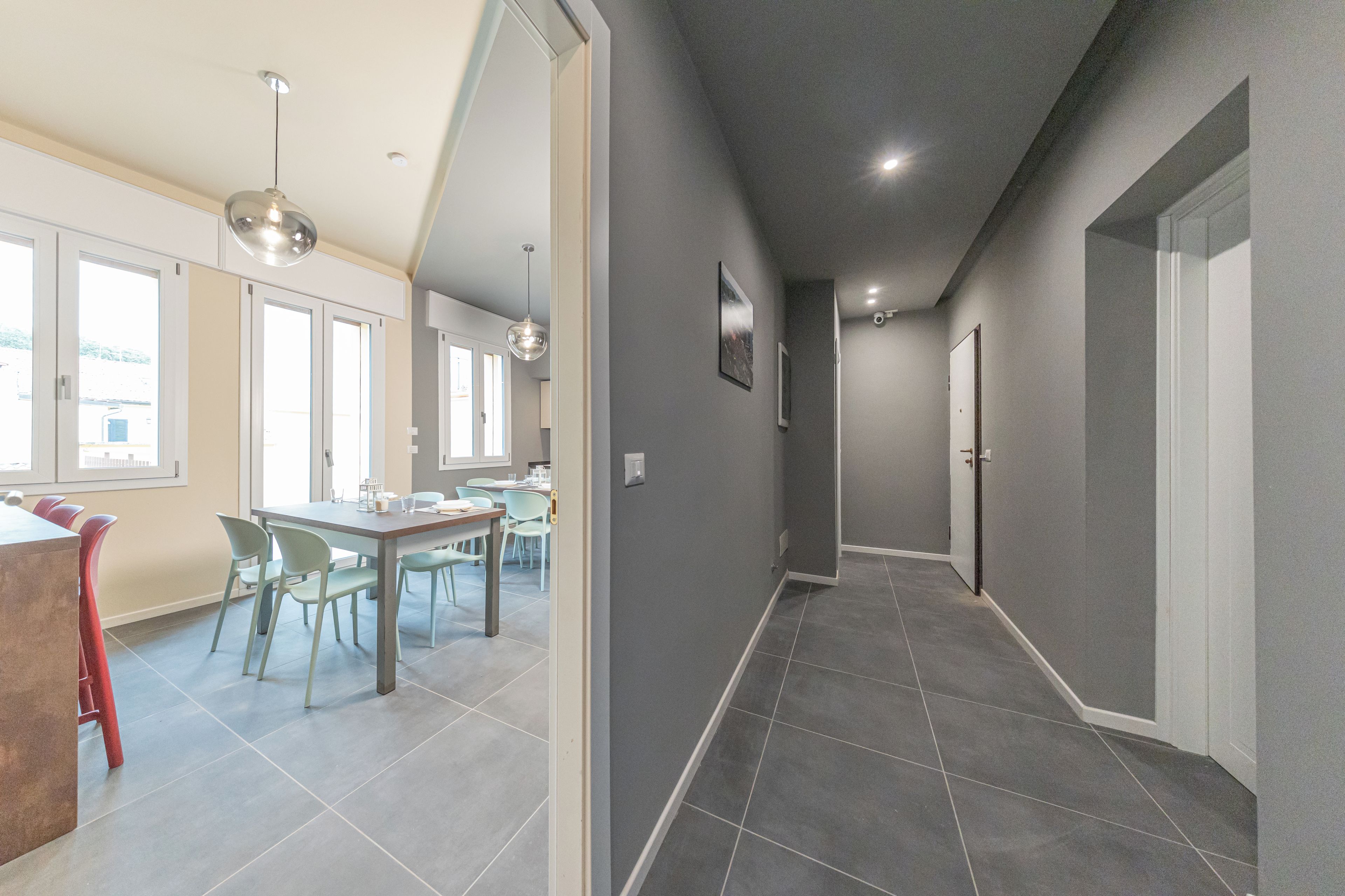 A modern interior with a dining area, a hallway, and a door leading to another room.