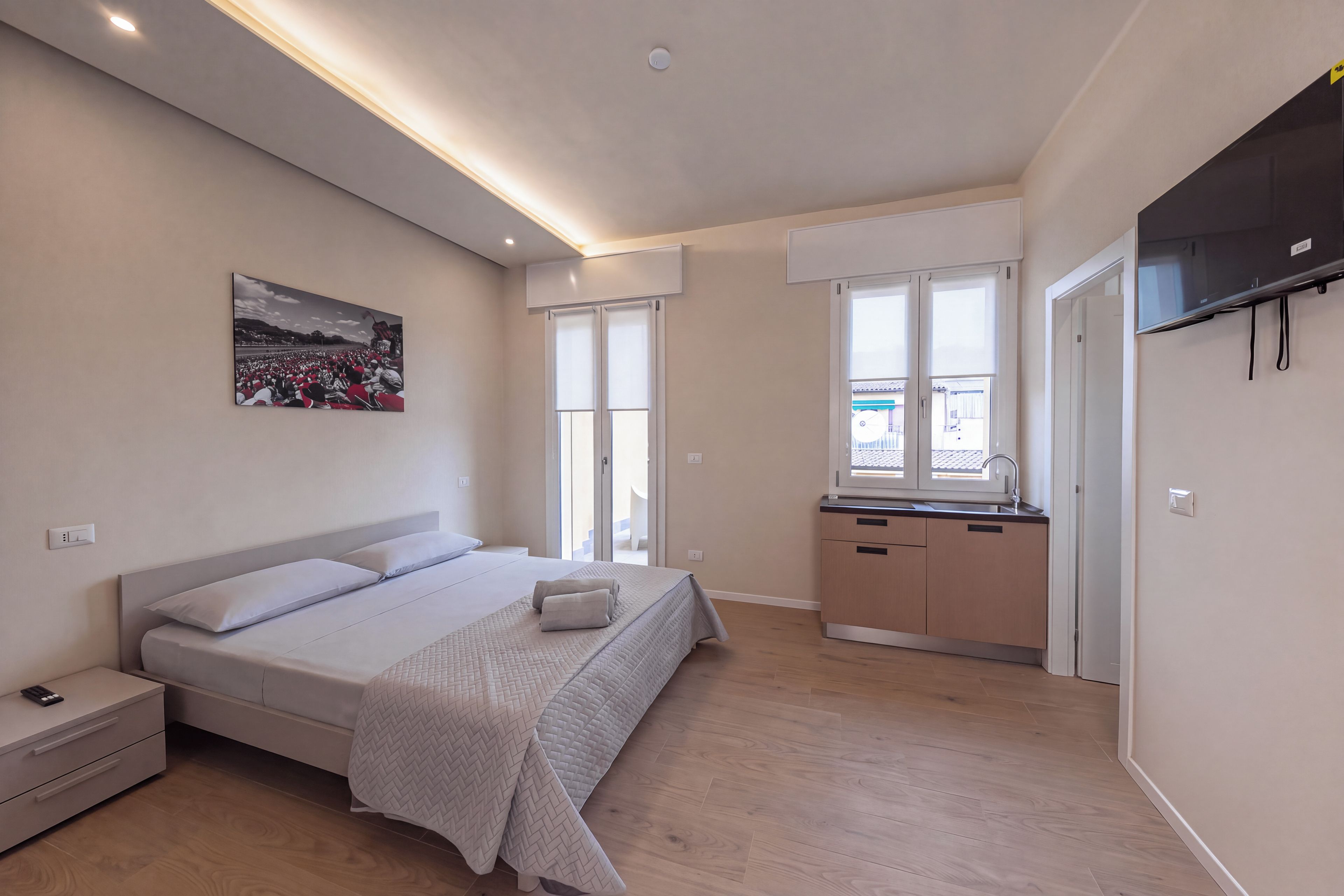A modern bedroom with a bed, bedside table, and a large window.