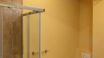 A bathroom with a glass shower enclosure, a toilet, and a bathtub.