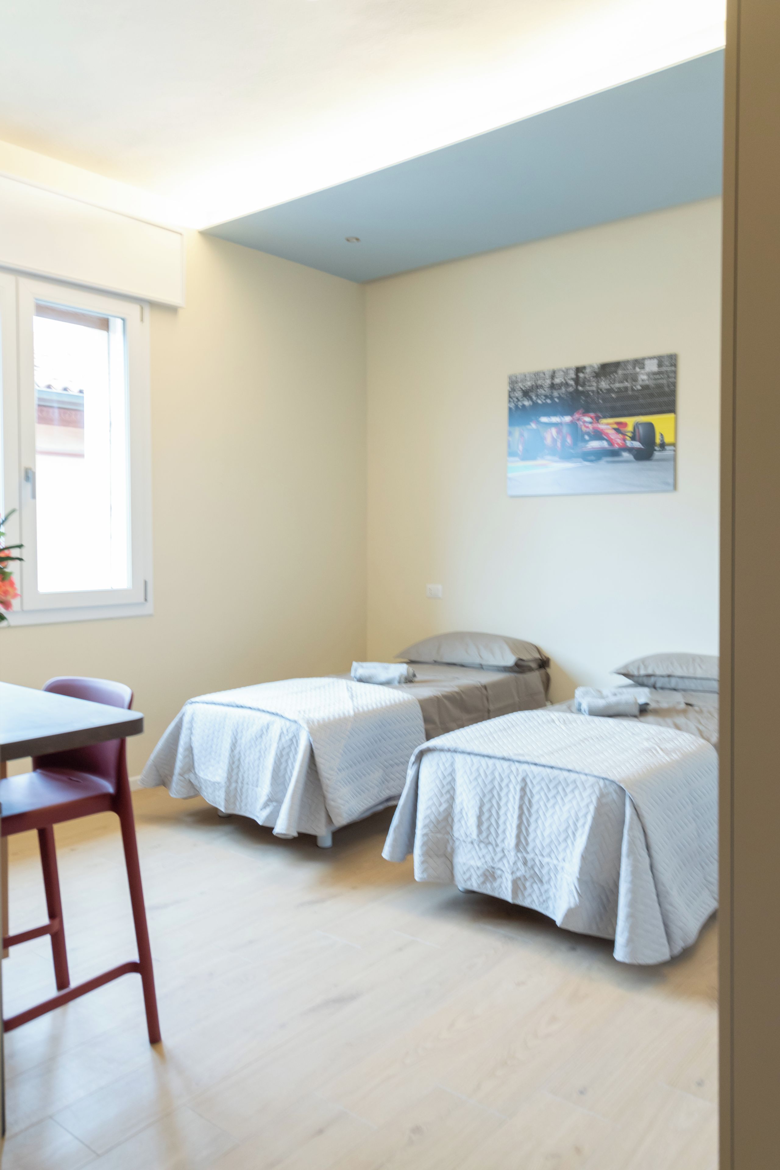 Una habitación con dos camas individuales, una mesita y una silla.