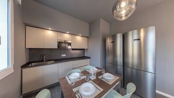 A modern kitchen with a dining area, stainless steel appliances, and a pendant light.
