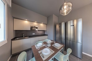 Una cocina moderna con comedor, electrodomésticos de acero inoxidable y una lámpara colgante.