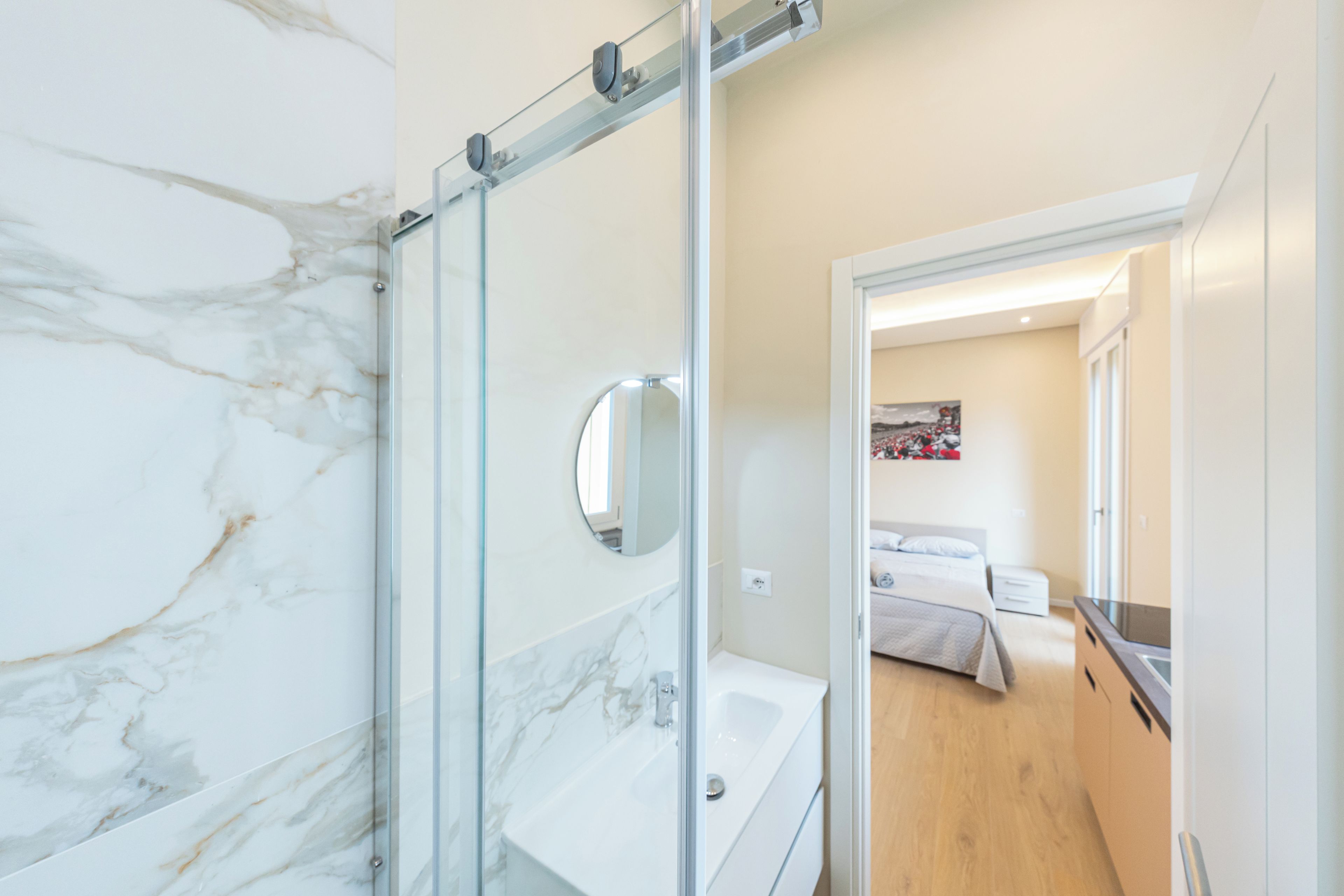 Un baño moderno con cabina de ducha de vidrio, lavamanos blanco y espejo.