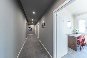 Un couloir qui comprend un coin repas avec une petite table et des chaises rouges.