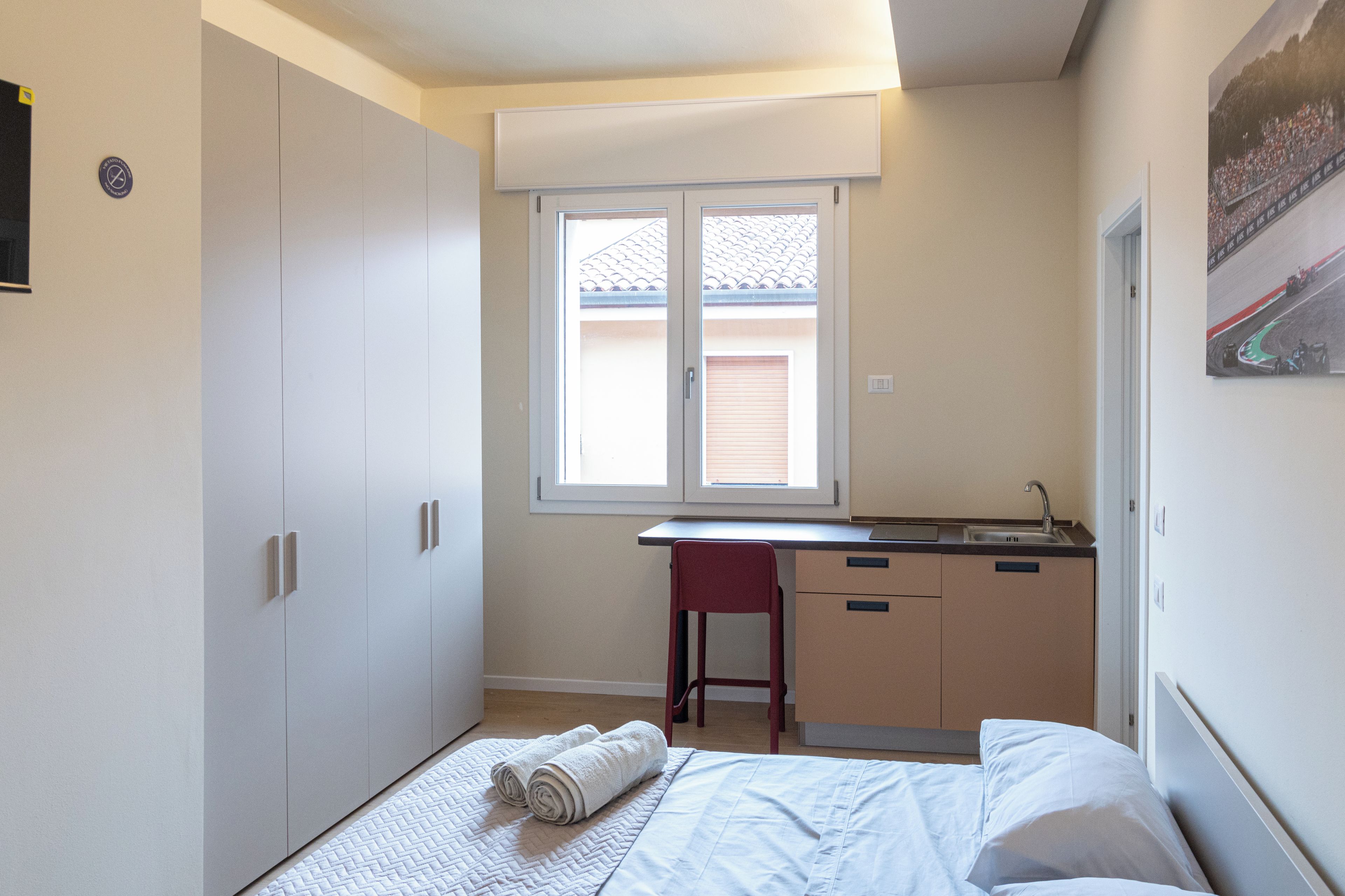 A small, compact room with a bed, a desk, and a window.
