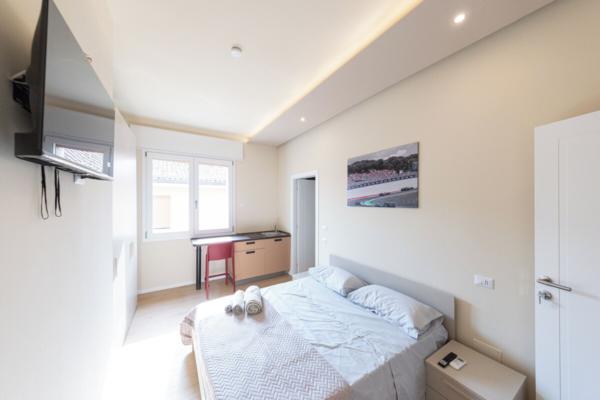 Un dormitorio con cama, escritorio y kitchenette.