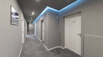 A hallway with grey walls, white doors, and a tiled floor.