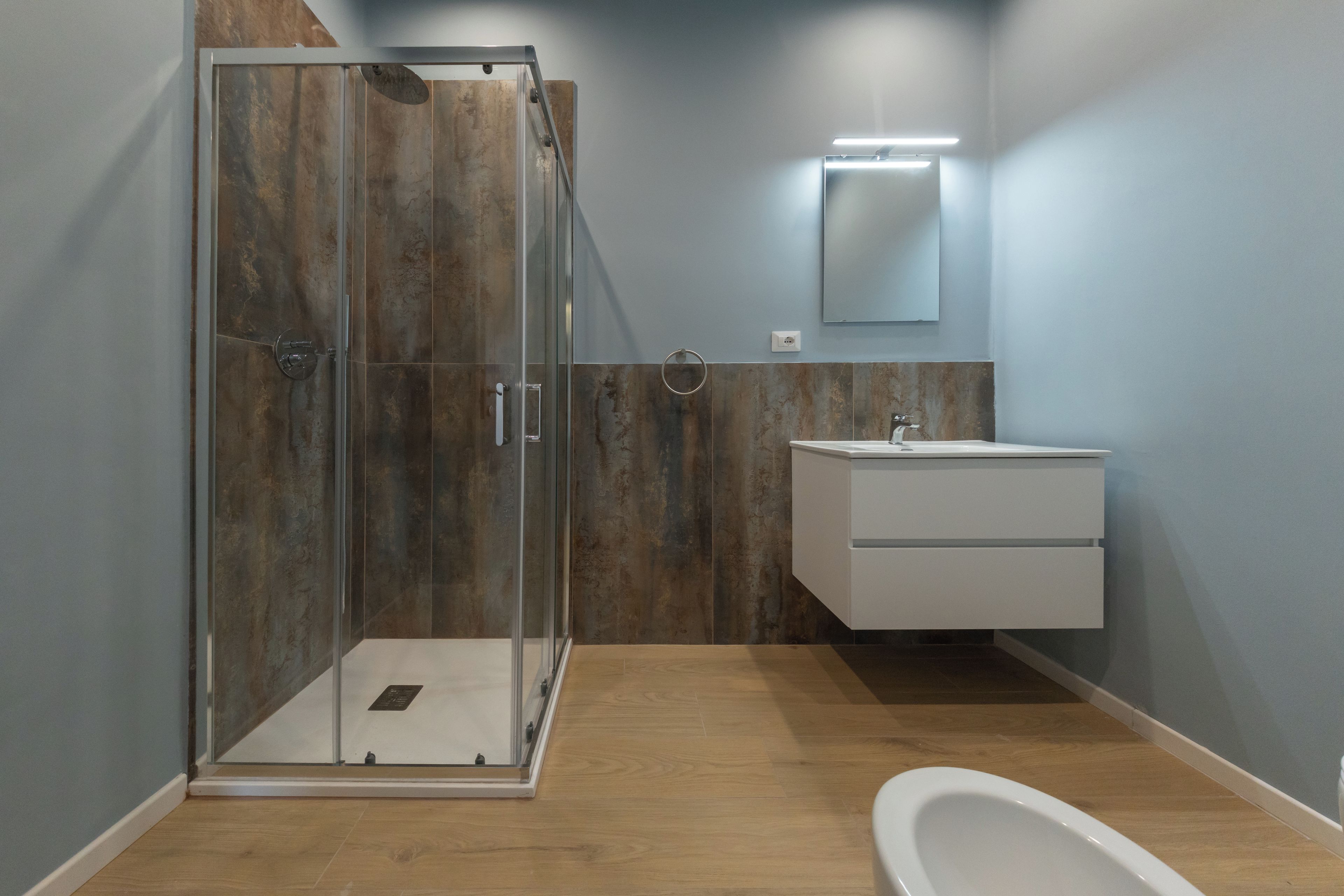 Un baño moderno con ducha envuelta en vidrio, un lavamanos blanco y un espejo.