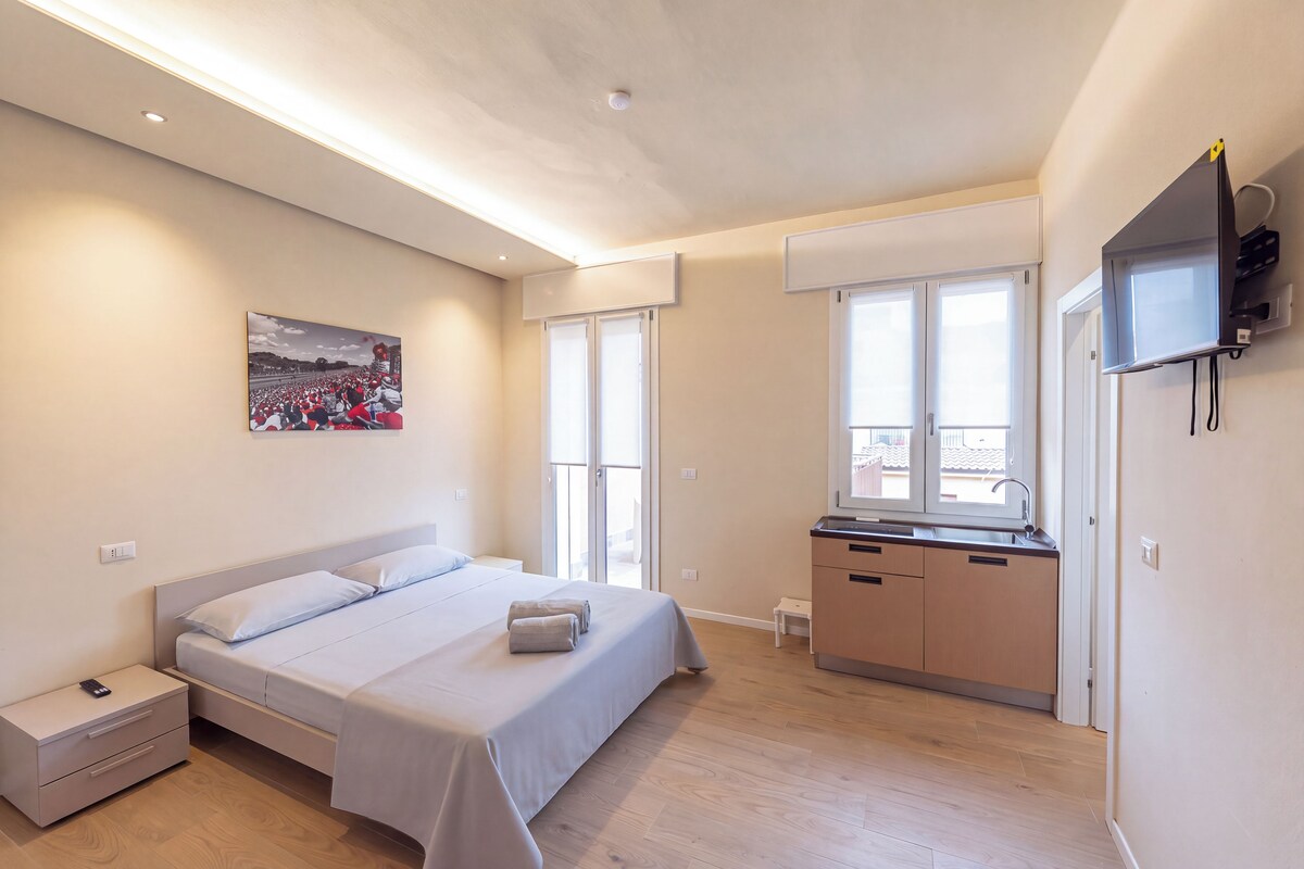 Un dormitorio moderno con cama, mesitas de noche, televisor y ventana con persianas.