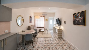 A modern living space with a dining area, a sofa, a TV, and a kitchen. - Casa Ruby- Stylish 1 bed apartment in town centre, 4min walk from the beach. (Fuseta)