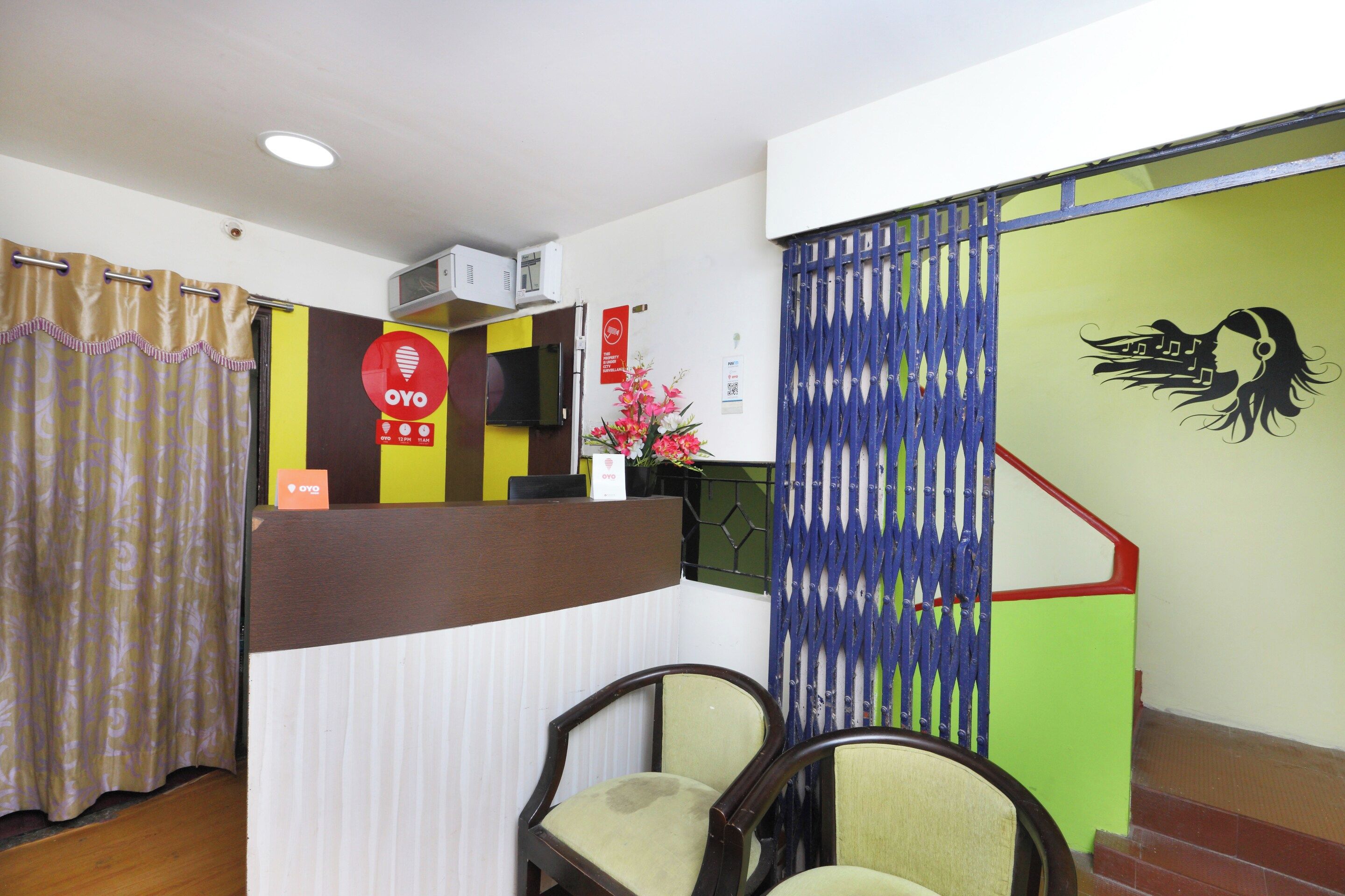 Zona de recepción con mostrador, sillas, televisor y una pared decorativa con una nota musical.
