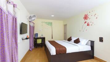 A hotel room with a bed, a desk, a chair, a television, and a wall decoration.