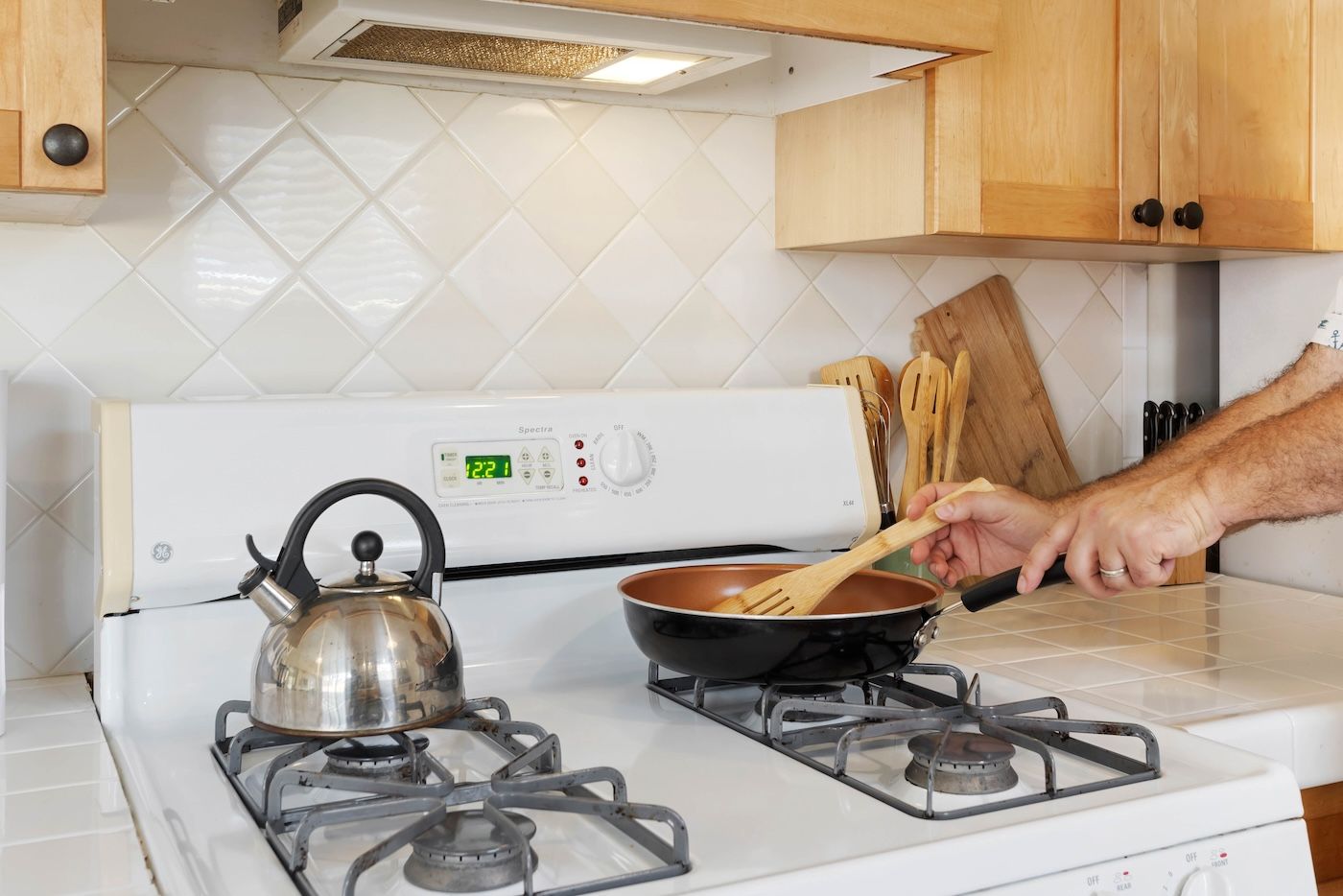 Una cocina con una estufa blanca, una tetera y una sartén sobre la estufa.