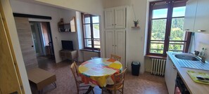 Una cucina compatta con un tavolo rotondo, un termosifone e una finestra vista verde.