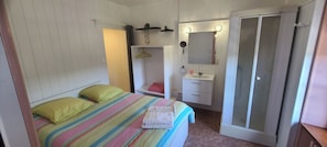 Una camera da letto con un letto, un comodino, uno specchio, una pianta sospesa e una porta scorrevole.