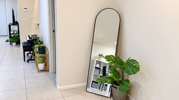 A hallway with a tiled floor, a large mirror leaning against the wall, and potted plants.