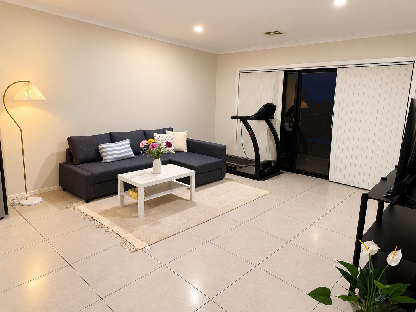 A modern living room with a sofa, coffee table, and a treadmill.