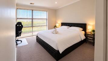 A hotel room with a large bed, a desk with a chair, and a view through the window.