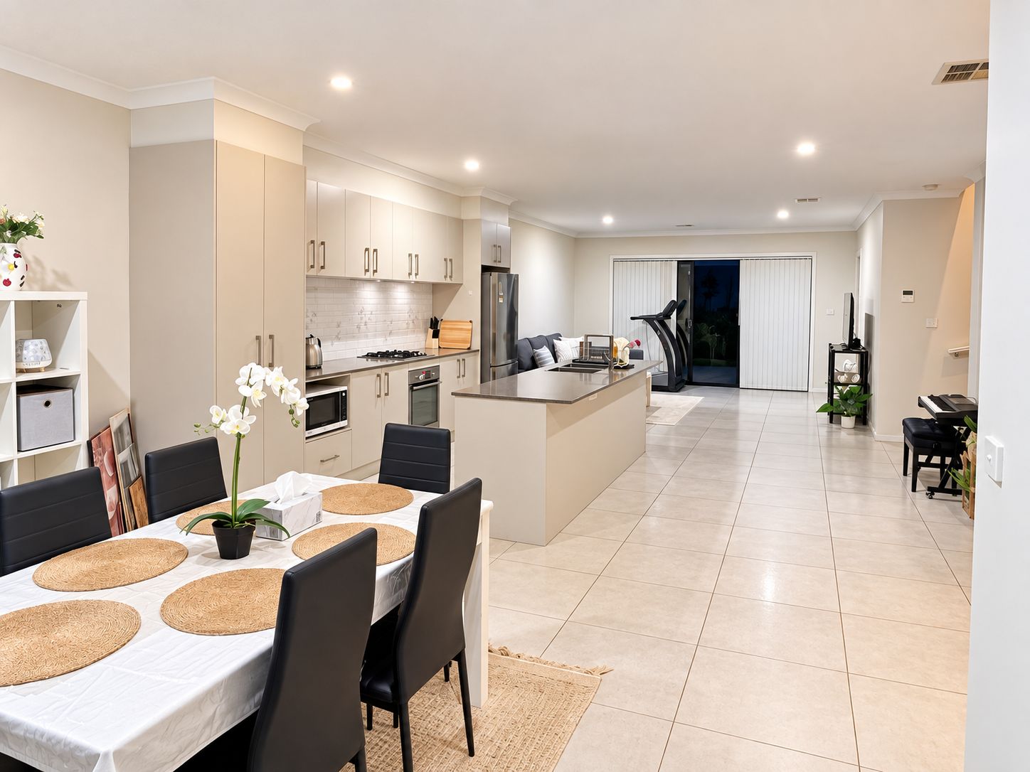 A modern kitchen with white cabinets, a central island, and a dining area with a table set for four.