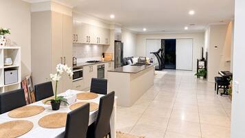 A modern kitchen with white cabinets, a central island, and a dining area with a table set for four.