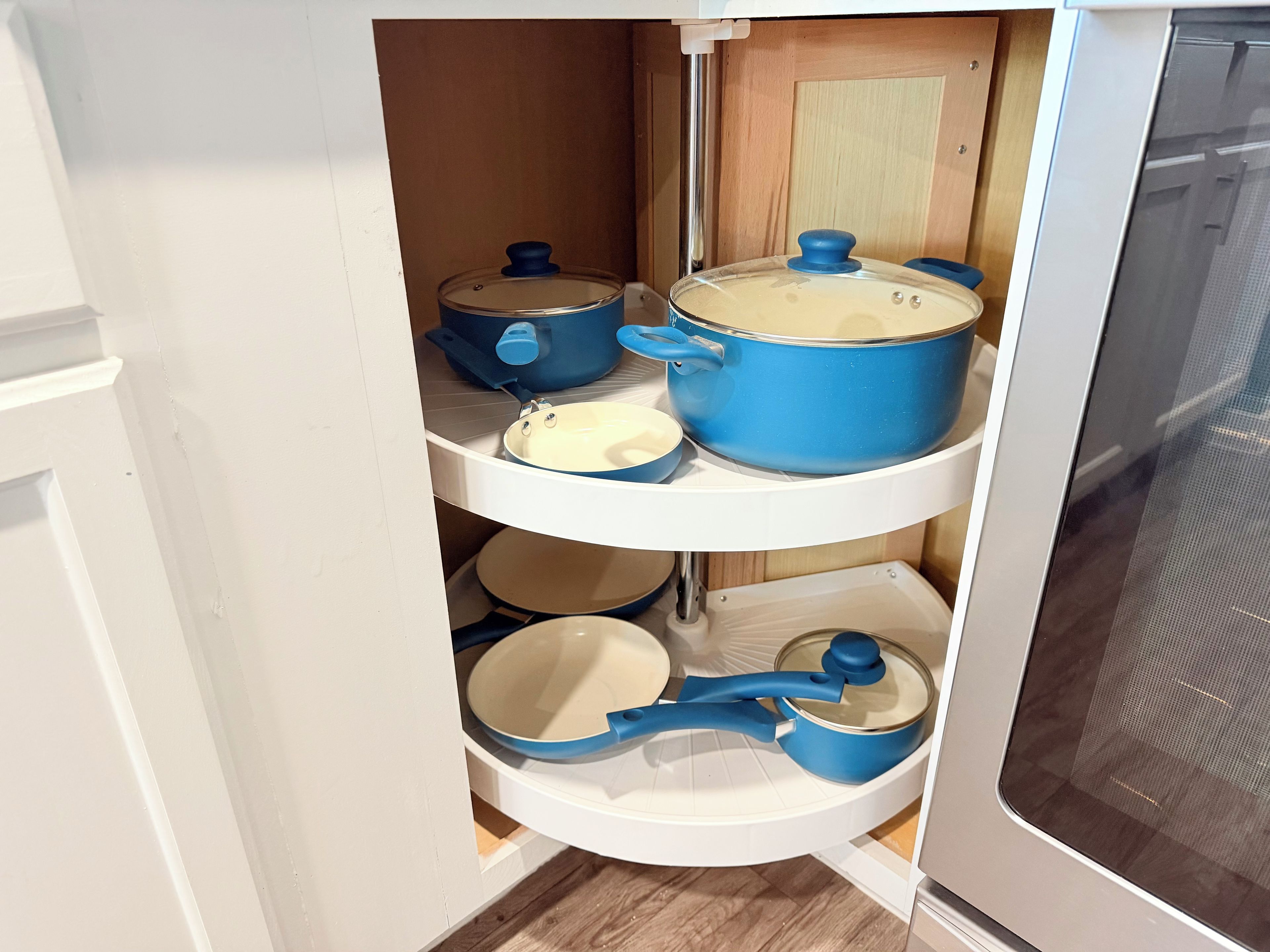 A kitchen with white cabinets, a microwave, and various pots and pans on shelves.