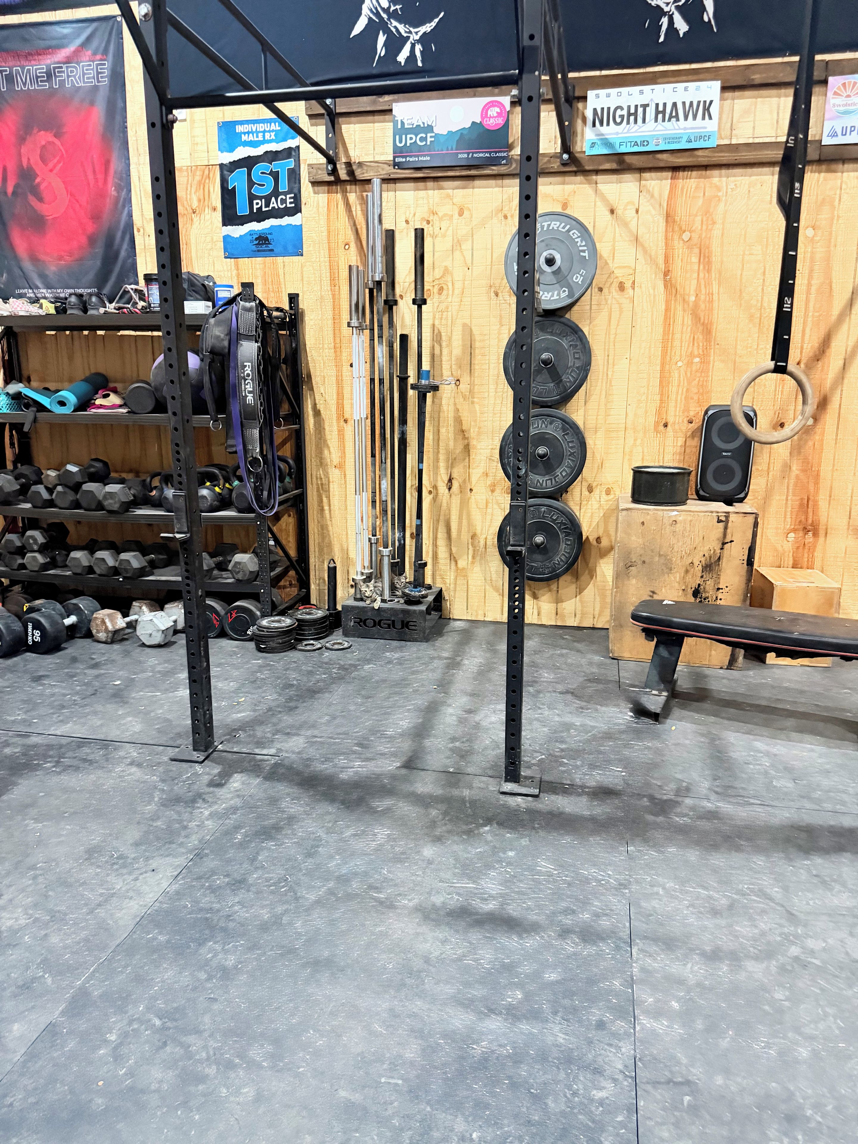 A gym with weightlifting equipment, a bench, and a wooden wall with various signs.