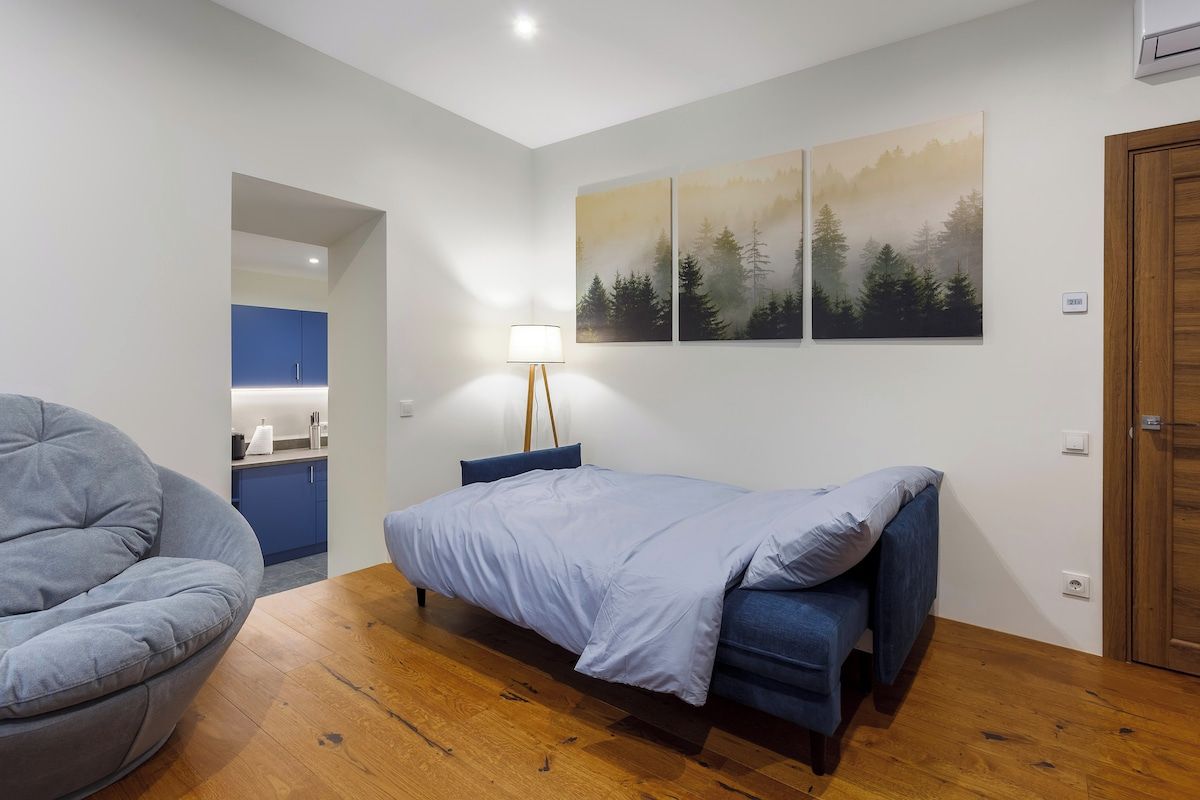 A bedroom with a bed, a chair, and a wall-mounted lamp.