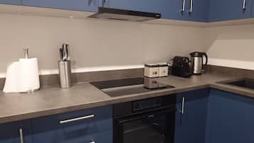 A kitchen with blue cabinets, a stainless steel coffee maker, a toaster, and a dish rack.