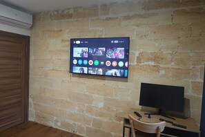 Et fjernsyn monteret på en murstensvæg, der viser forskellige streamingtjenester.