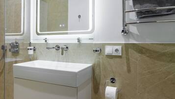 A modern bathroom with a glass-enclosed shower, a white sink with a mirror, and a towel rack with a gray towel.