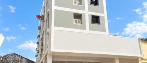A multi-story building with a flat roof and a covered entrance area.