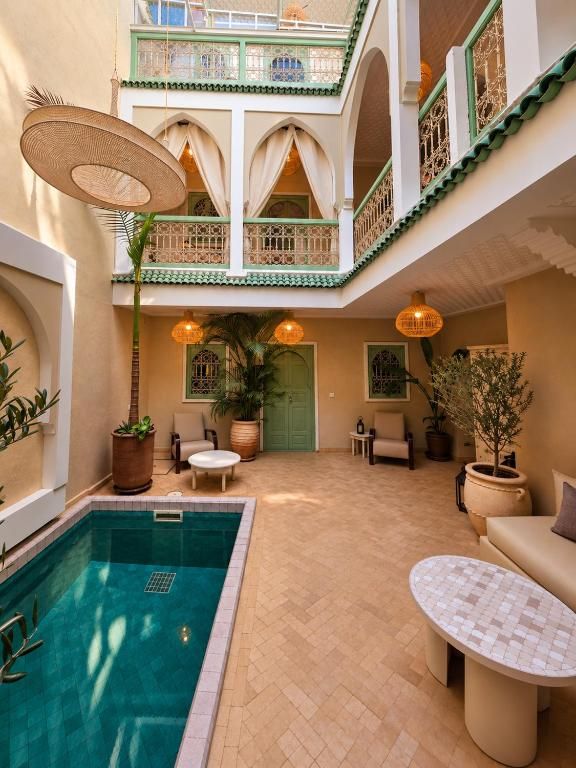 Une cour avec une piscine, des espaces aménagés pour s’asseoir et des plantes en pot.