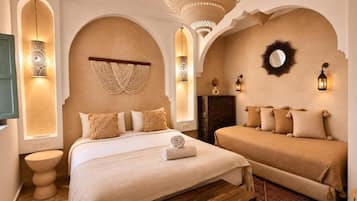 Une chambre d’hôtel avec un grand lit, un petit canapé, un banc en bois et un tapis à motifs.