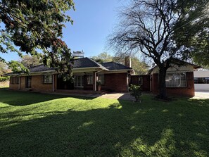 A two-story house with a brick exterior, a covered porch, and a well-maintained lawn. - Hillside Home Bulawayo (Bulawayo)