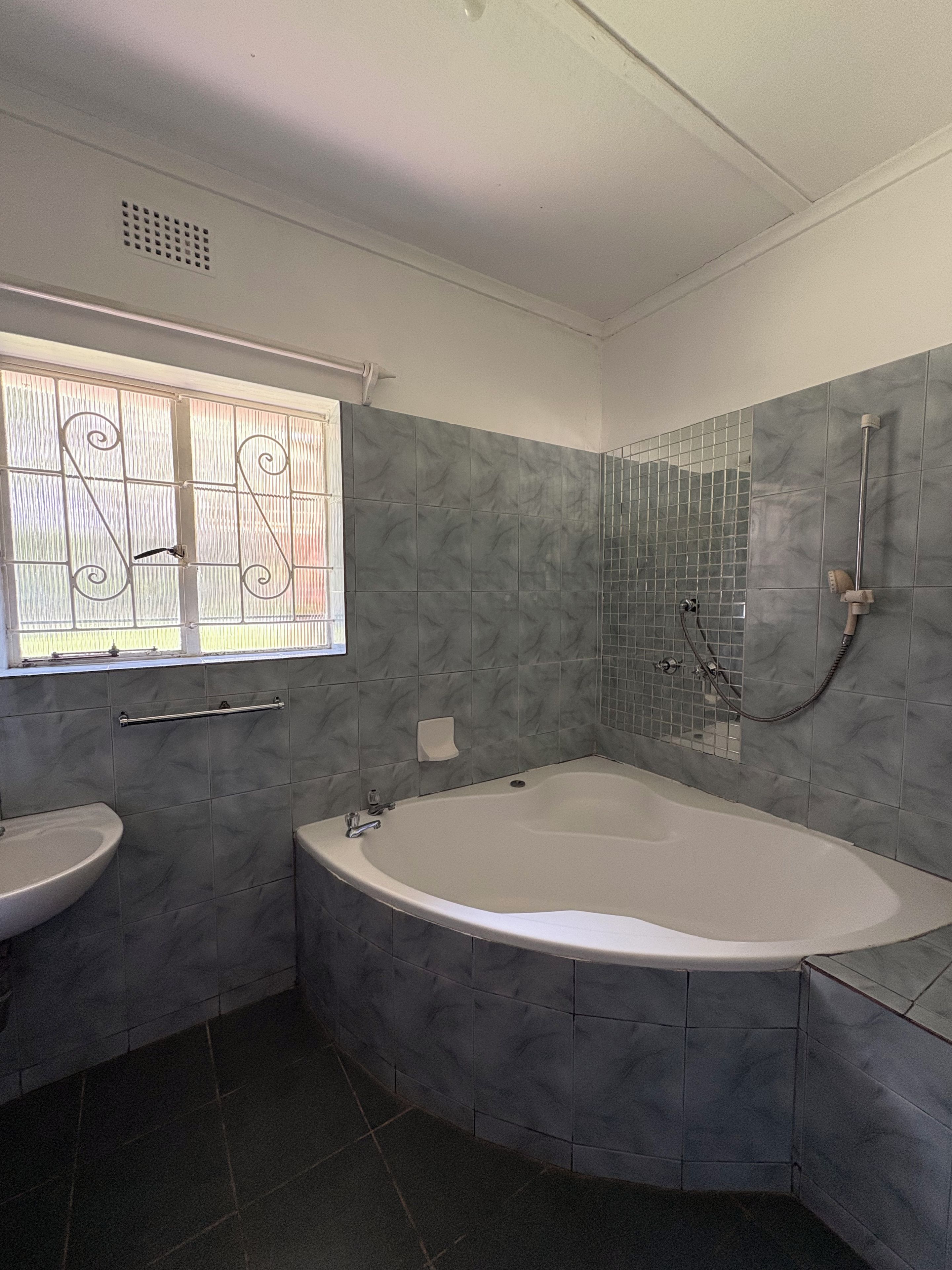 Une salle de bain avec une baignoire, un lavabo et une fenêtre ornée de barreaux décoratifs.