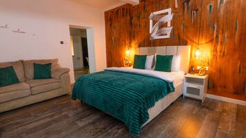 Een slaapkamer met een bed, nachtkastje, bank en een wand van hout.