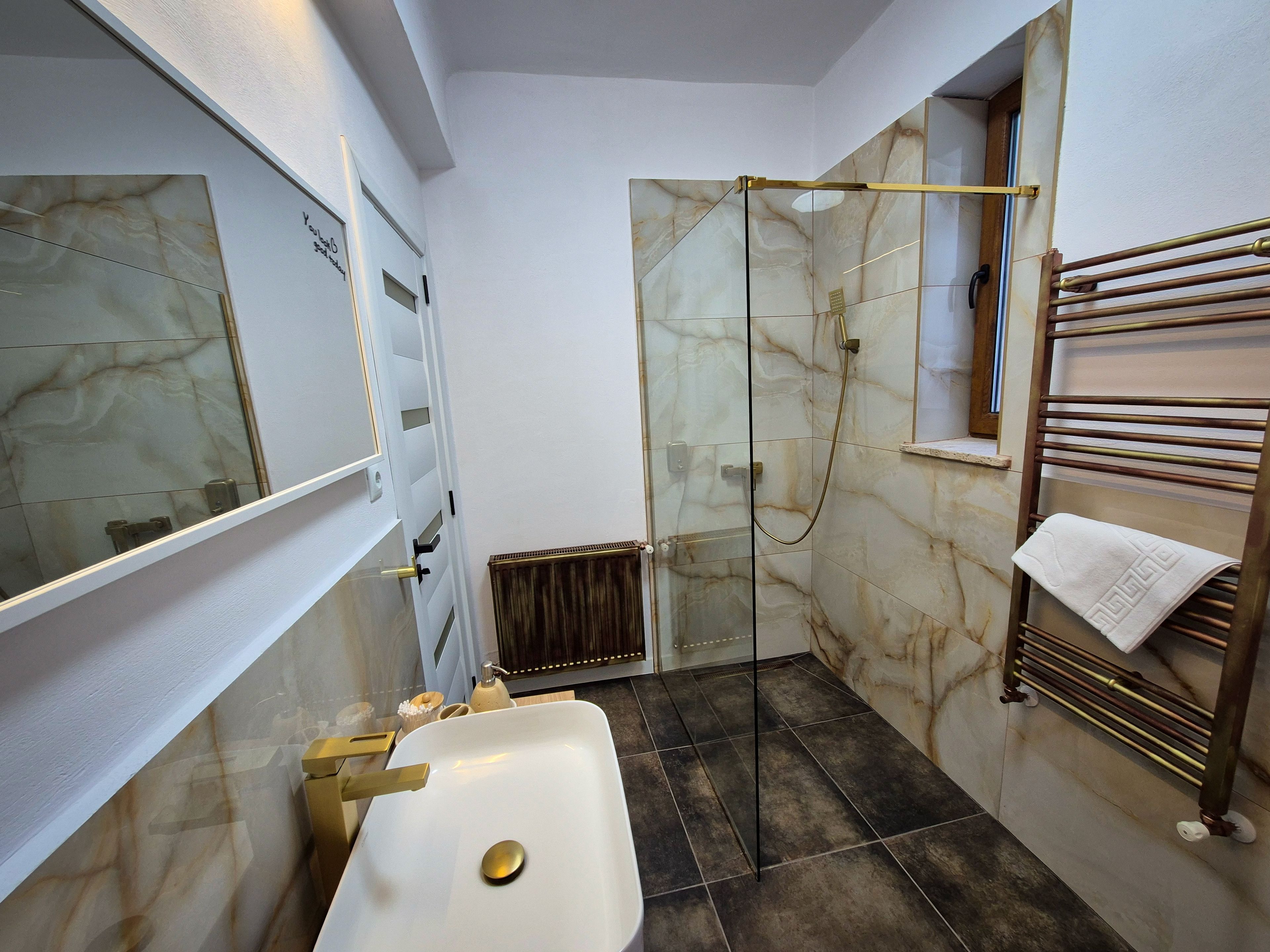 A bathroom with a glass-enclosed shower, a white sink, and a towel rack.