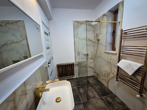 Ein Badezimmer mit einer Duschkabine, einem weißen Waschbecken und einem Handtuchhalter.