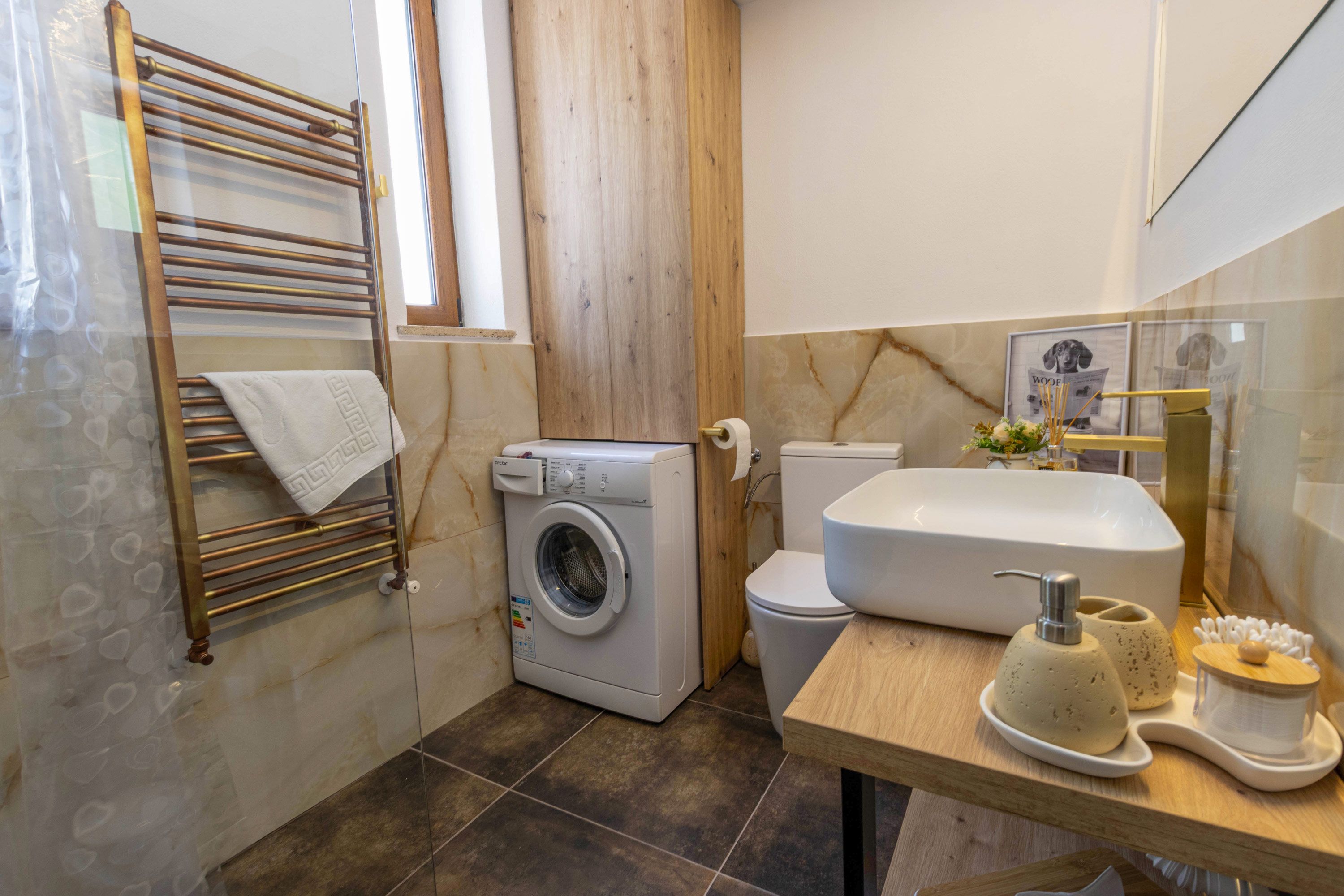Een kleine badkamer met een wasmachine, toilet en wastafel.