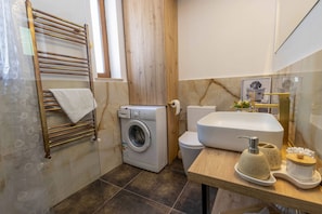 Ein kleines Badezimmer mit Waschmaschine, Toilette und Waschbecken.