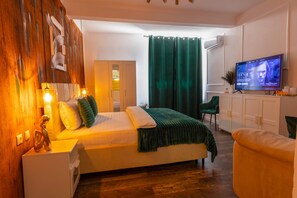Ein Schlafzimmer mit einem Bett, Nachttischen, einem Fernseher, einem grünen Vorhang und einer Holzwand.