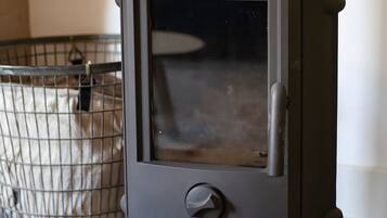 Un poêle à bois noir avec une porte en verre, une cage en métal et des carreaux de sol à motifs.