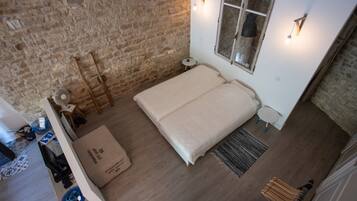 Een slaapkamer met een tweepersoonsbed, een klein rond tafeltje, een ladder en een raam met uitzicht.