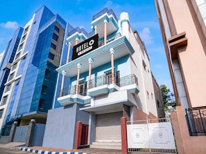 A hotel with a modern facade, balconies, and a sign indicating it is fully serviced. - Deluxe PG Guest House (Barasat)