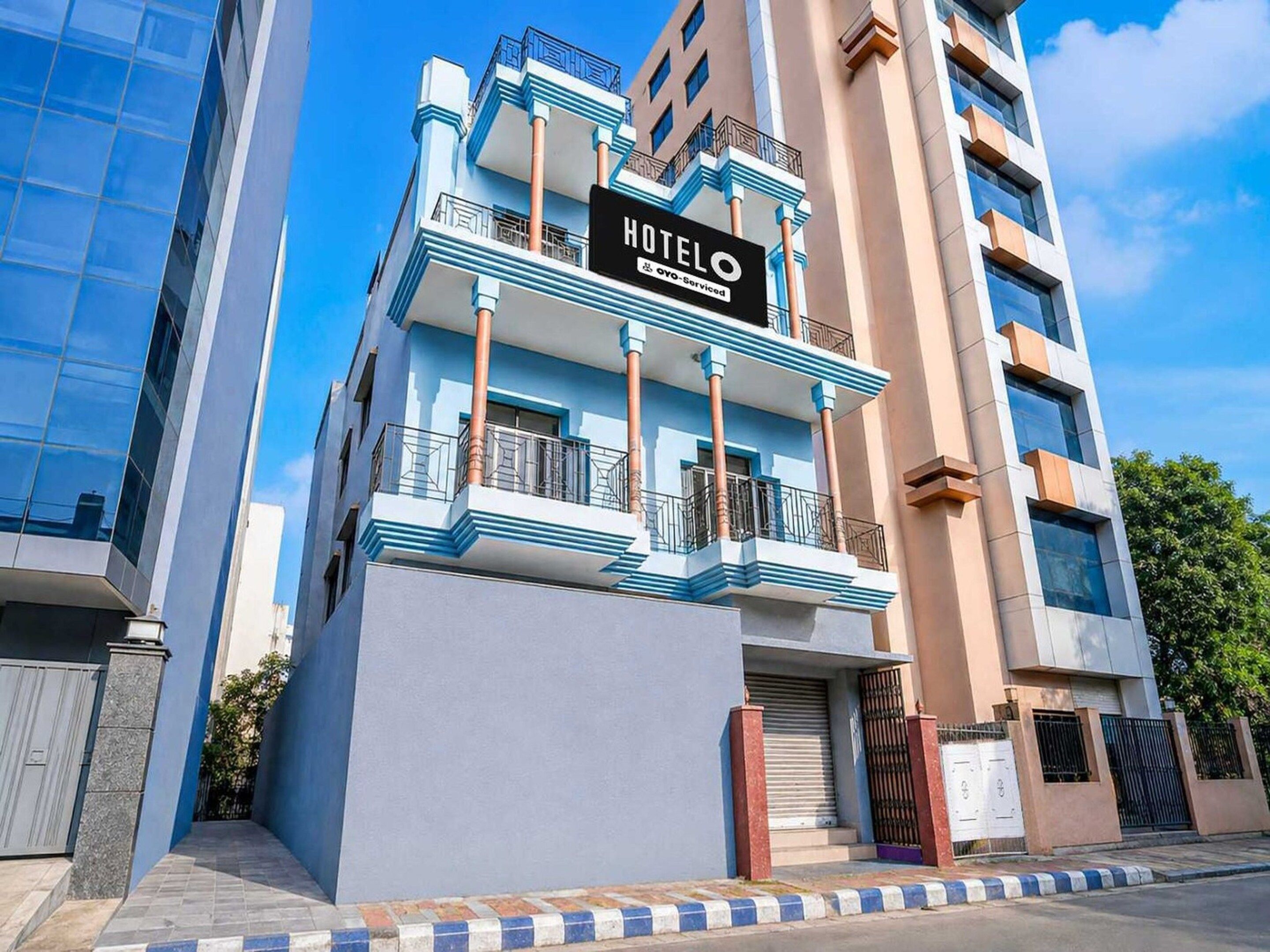 Un hotel con un letrero llamativo, fachada moderna y entrada protegida por una reja.