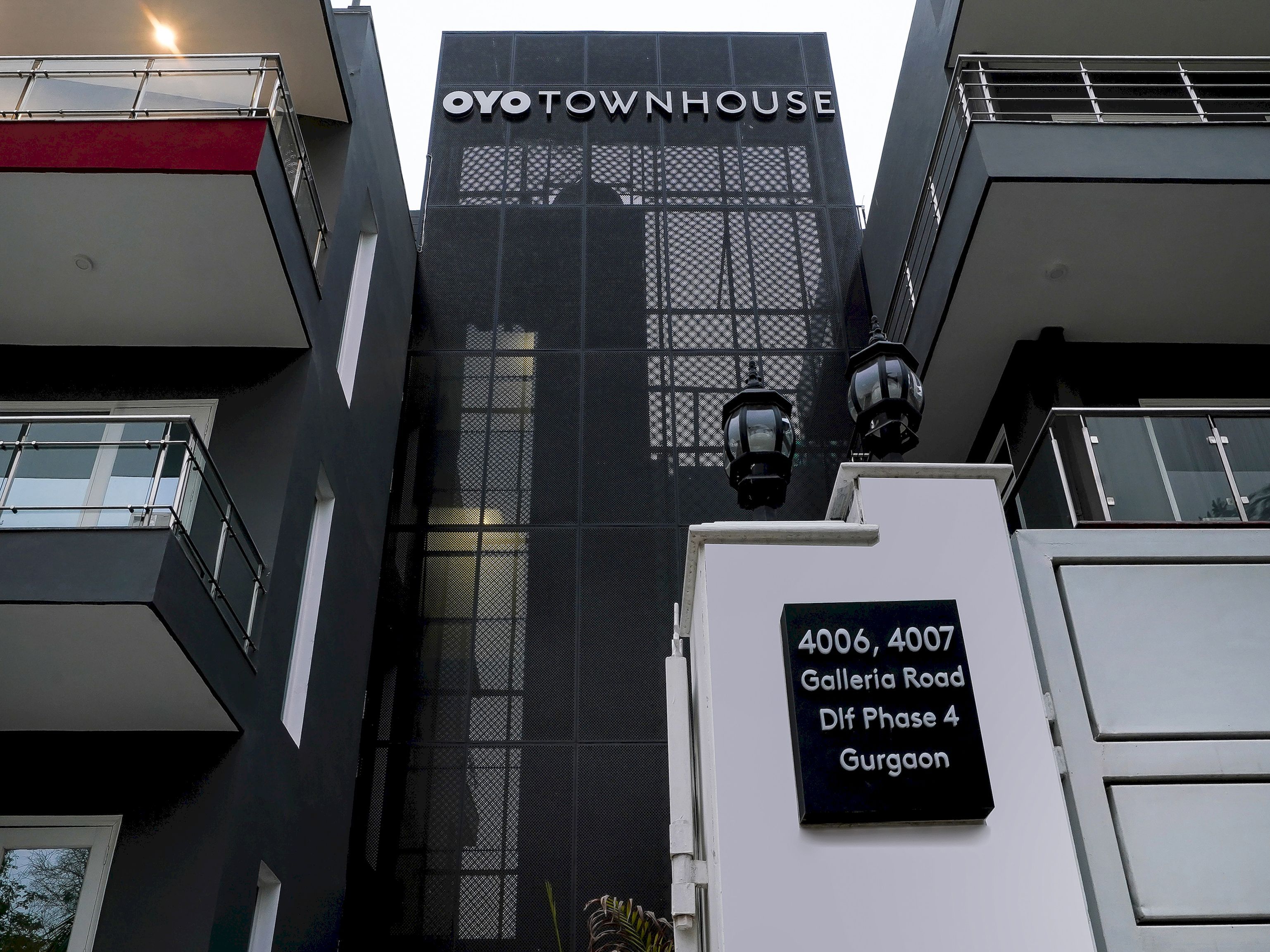 Un edificio con un cartel que dice 'OYO TOWNHOUSE' y un cartel debajo que indica '4006, 4007 Galleria Road Dlf Phase 4 Gurgaon'.